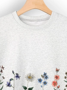 Detail of colorful floral print on light grey cotton blend sweatshirt with ribbed hem
