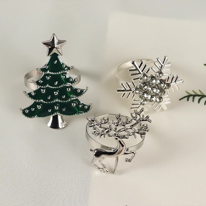 Detailed view of silver deer, enamel Christmas tree, and rhinestone snowflake napkin rings