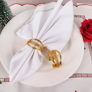 Ronds de serviette élégants en métal doré sur assiette blanche avec décor festif