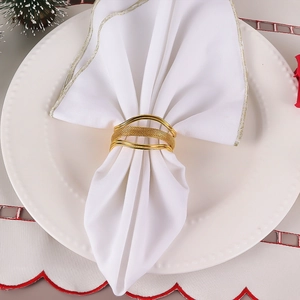 Rond de serviette doré en métal tissé au design ondulé sur une assiette blanche