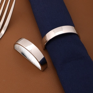 Minimalist silver semicircular metal napkin ring on navy fabric over brown leather