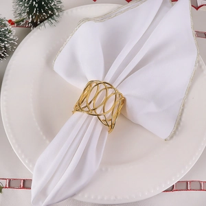 Golden woven X-shaped hollow napkin ring on white fabric for elegant table setting