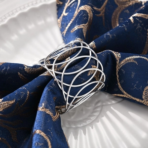 Macro shot of silver metal napkin ring with hollow geometric circles on blue fabric