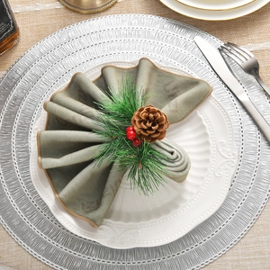Christmas napkin ring with pine needles, red berries and pine cone on green velvet cloth