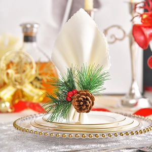 Christmas napkin ring with pine needles and red berries on a white napkin at a dinner table