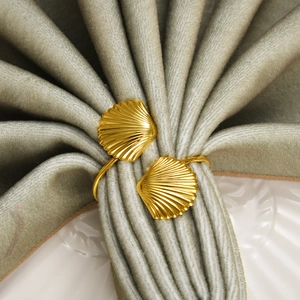 Golden seashell napkin ring with dual scallop design on green velvet fabric