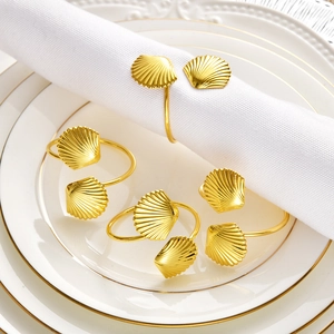 Detailed close-up of golden shell napkin rings on a white plate with elegant napkins