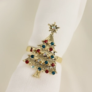 Dettaglio portatovagliolo a forma di albero di Natale dorato con strass colorati su bianco