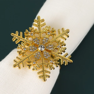 Golden snowflake napkin ring with sparkling rhinestones on a white linen napkin