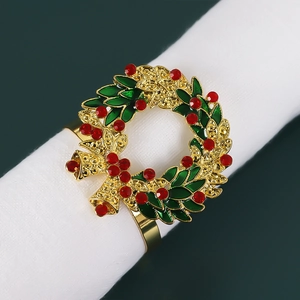Close-up of golden Christmas wreath napkin ring with green enamel and red rhinestones