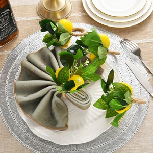 Handmade artificial lemon napkin ring with green leaves and twine on a grey napkin