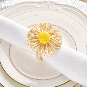 Close-up of handmade straw flower napkin ring on white plate with natural textures
