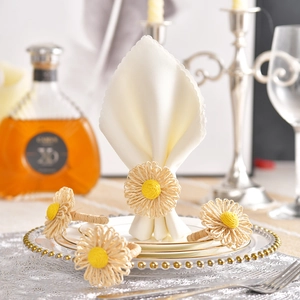 Close-up of handmade straw daisy napkin rings on white fabric with elegant tableware