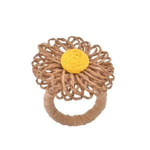 Handmade bohemian straw flower napkin ring with yellow petals on a clean white background