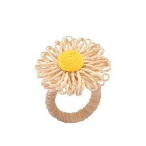 Macro detail of Bohemian handmade straw napkin ring with yellow daisy floral design
