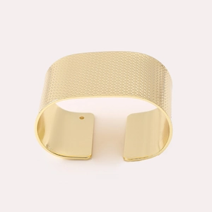 Matte gold wide C-shaped metal napkin ring with textured grid pattern for table setting