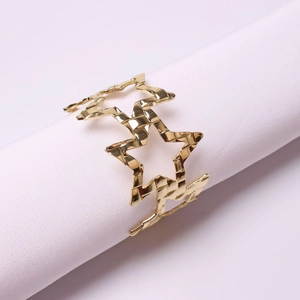 Close-up of gold hollow star napkin ring holder on a white fabric for table decor