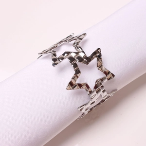 Close-up of silver hollow star napkin ring with hammered texture on white cloth