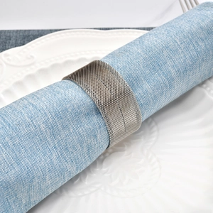 Silver woven metal mesh napkin ring on light blue linen napkin with white plate