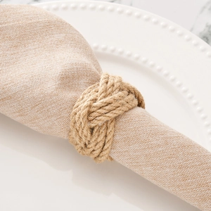 Handmade brown jute rope woven napkin ring displayed on white plate with linen fabric