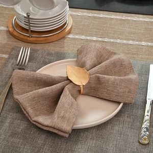 Elegant gold leaf napkin ring with metallic texture on a rustic linen napkin