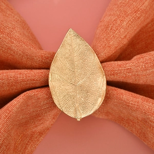 Detailed view of a golden leaf napkin ring with intricate vein textures on fabric