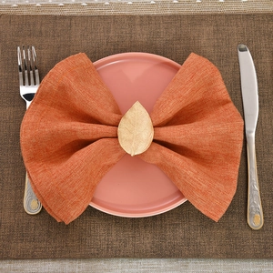 Close-up of golden leaf napkin ring with detailed vein texture on a warm setting