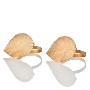 Detailed macro view of gold metal leaf napkin rings with textured veins and matte finish