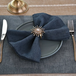 Elegant gold fireworks napkin ring with pearl and rhinestones on blue fabric