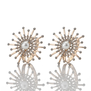 Detailed view of two gold napkin rings with radial sunburst design and central pearl