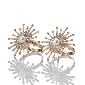 Macro detail of gold plated firework napkin rings with pearls and sparkling rhinestones