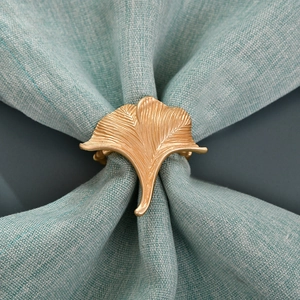 Macro shot of golden ginkgo leaf napkin ring with detailed veins on blue linen fabric