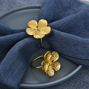 Detail of gold plum blossom napkin rings showing textured petals and floral design