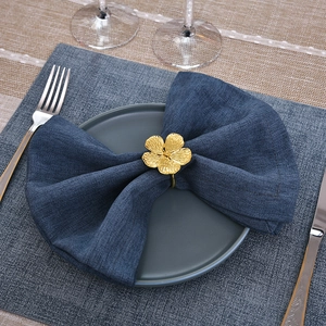 Detailed close-up of a golden flower napkin ring on a navy blue linen napkin