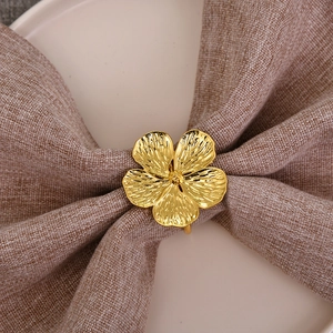Golden plum blossom napkin ring with brushed texture on elegant ceramic table setting