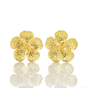 Close-up of golden flower stud earrings with brushed petal texture and mirror reflection
