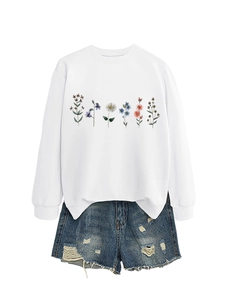 Close-up of six colorful floral prints on a white cotton long-sleeve crewneck sweatshirt