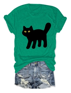 Flat lay of a green T-shirt with a black cat print and ripped denim shorts on white background