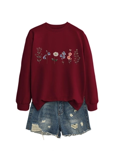 Detail of colorful daisy print on a burgundy long-sleeve sweatshirt with denim shorts