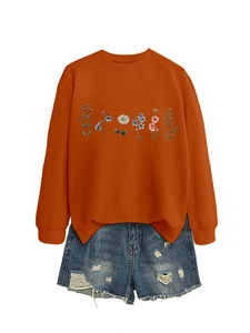Detail of colorful floral pattern on a burnt orange round neck long sleeve sweatshirt