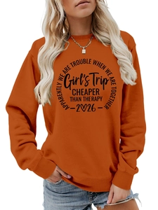 Detail of orange crewneck sweatshirt with black slogan about travel and friendship