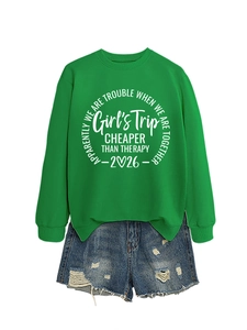 Flat lay of bright green sweatshirt featuring Girl's Trip 2026 text with denim shorts