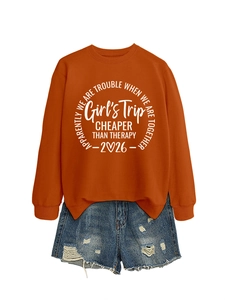 Close-up of rust red sweatshirt with 'Girl's Trip' print and distressed denim shorts