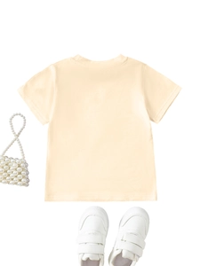Flat lay of cream yellow kids short sleeve t-shirt with pearl bag and white shoes