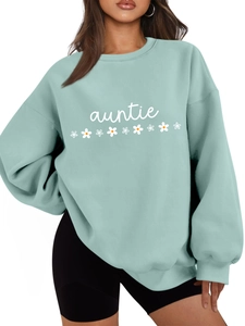 Détail du sweat vert menthe avec texte auntie et imprimé de petites marguerites