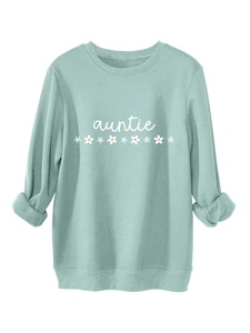 Détail du sweat vert menthe avec texte auntie blanc et imprimé floral de pâquerettes