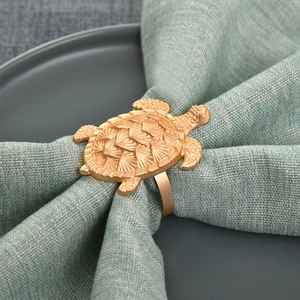 Goldener Schildkröte Serviettenring mit Reliefstruktur auf grünem Stoff und dunklem Teller