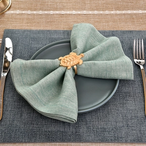 Makro-Detail des goldenen Schildkröten-Serviettenrings mit Textur auf grüner Serviette