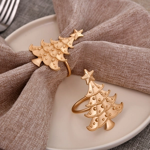 Macro detail of golden Christmas tree napkin ring on linen cloth with festive table setting