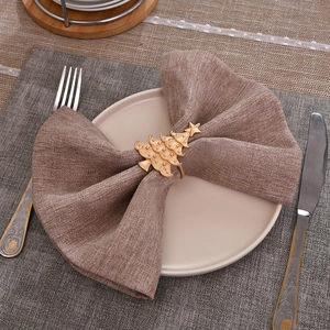 Golden Christmas tree metal napkin ring on a dark bow on a western dining table setting